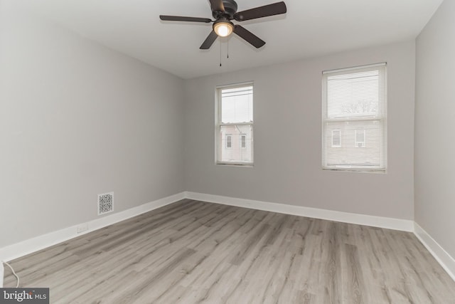 unfurnished room with a ceiling fan, wood finished floors, visible vents, and baseboards