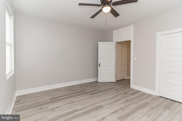 unfurnished bedroom with multiple windows, light wood-type flooring, and baseboards