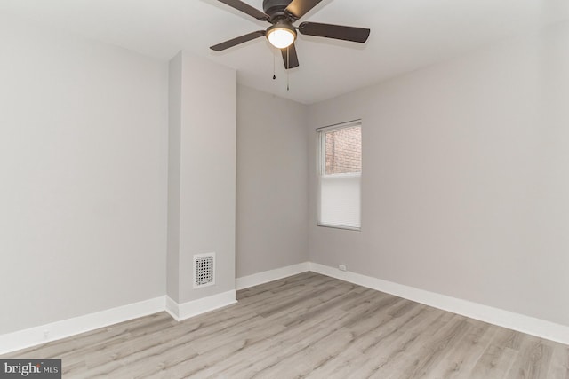 spare room with wood finished floors, visible vents, and baseboards