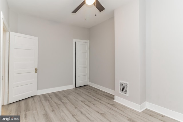 empty room featuring a ceiling fan, visible vents, light wood-style flooring, and baseboards