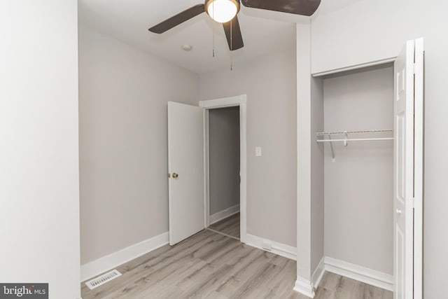 unfurnished bedroom with baseboards, a closet, visible vents, and wood finished floors