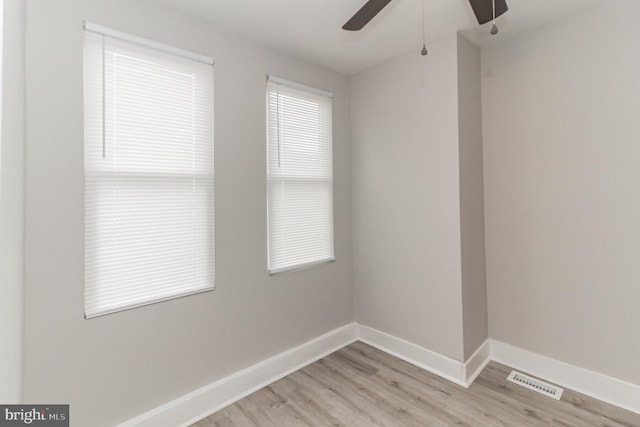 unfurnished room with light wood finished floors, a ceiling fan, visible vents, and baseboards