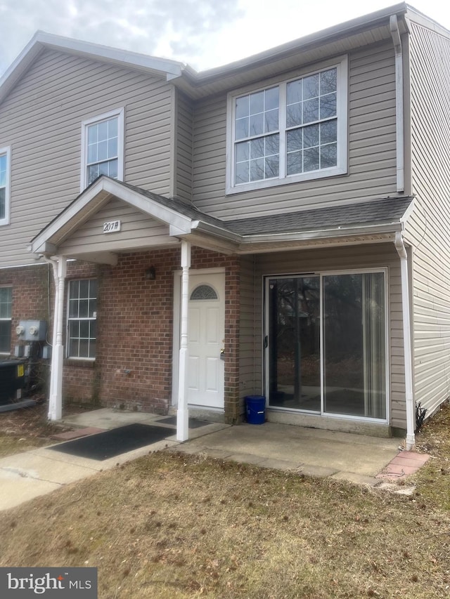 view of front of property with brick siding and roof with shingles