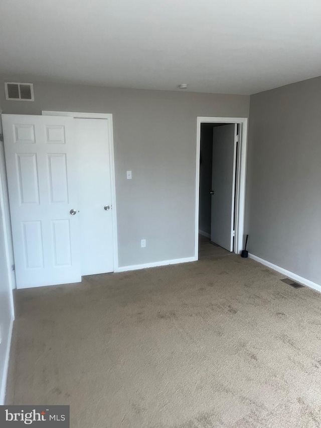 carpeted empty room featuring visible vents and baseboards