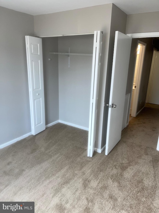 unfurnished bedroom featuring a closet, carpet flooring, and baseboards