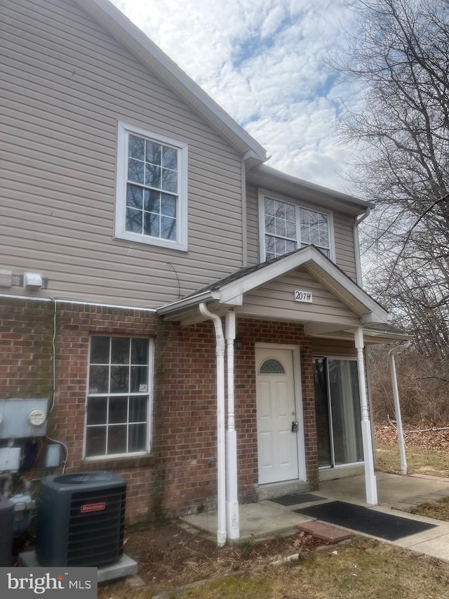 property entrance featuring central AC and brick siding