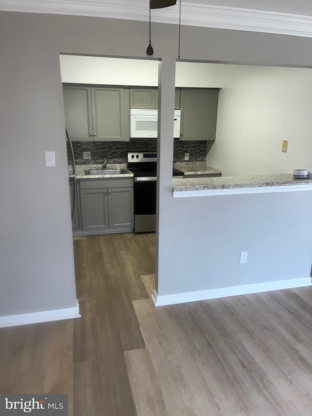 kitchen featuring stainless steel electric range oven, gray cabinets, white microwave, ornamental molding, and a sink