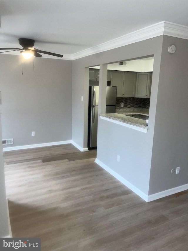 kitchen featuring ornamental molding, wood finished floors, visible vents, and tasteful backsplash