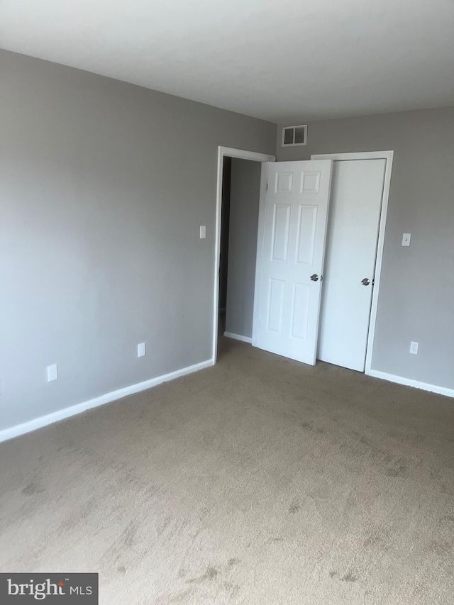 unfurnished bedroom with carpet floors, a closet, visible vents, and baseboards