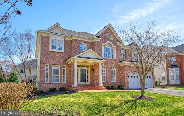 colonial-style house with brick siding, a garage, driveway, and a front yard