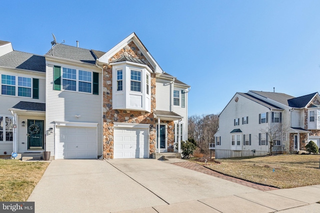 view of front of property featuring stone siding, an attached garage, driveway, and a front yard