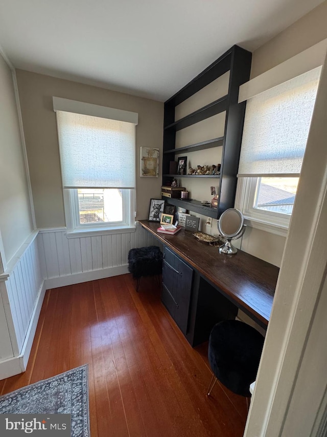 office with a wainscoted wall, wood-type flooring, and built in desk