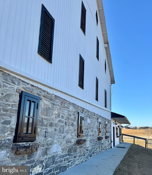 view of side of property featuring stone siding and fence