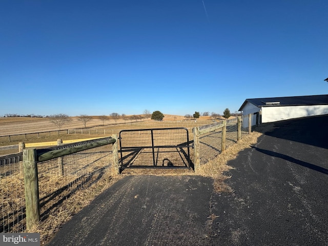 exterior space featuring aphalt driveway, a gate, and a rural view