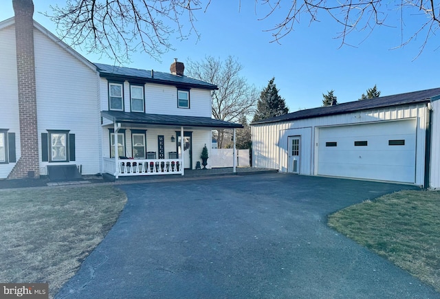 view of front of property featuring a garage, an outbuilding, covered porch, and a chimney