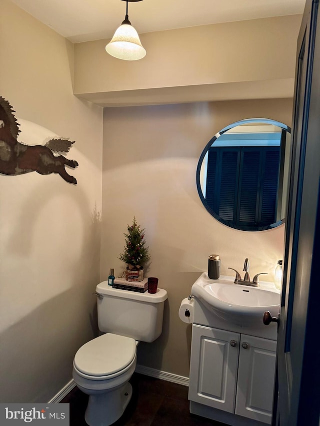 bathroom featuring toilet, vanity, and baseboards