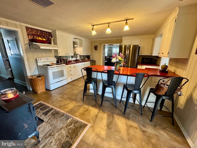 kitchen featuring electric stove, dark countertops, freestanding refrigerator, and white cabinets