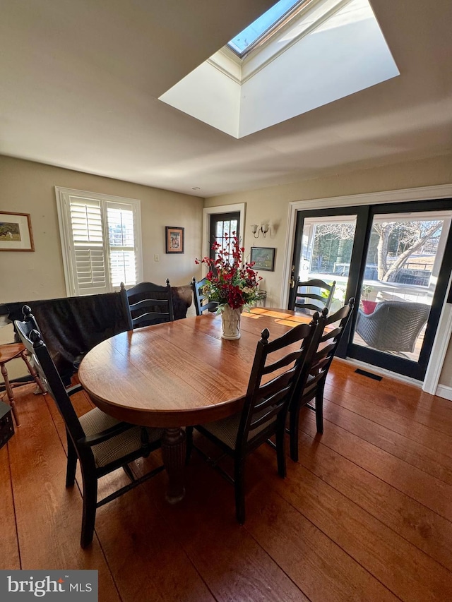 dining space featuring hardwood / wood-style floors, a skylight, and visible vents