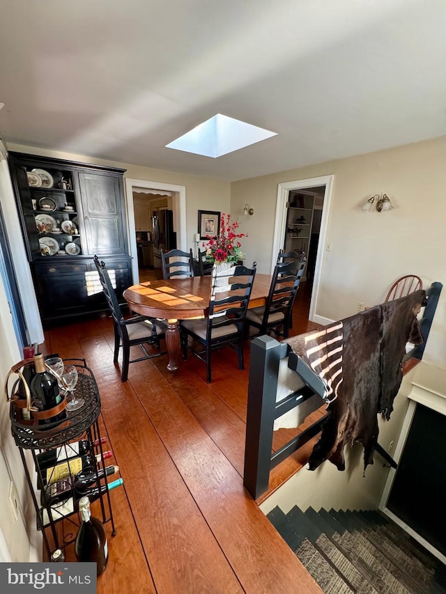 dining area with a skylight and hardwood / wood-style floors