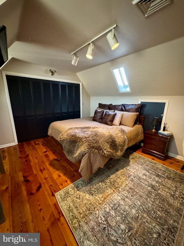 bedroom featuring lofted ceiling, baseboards, visible vents, and wood finished floors