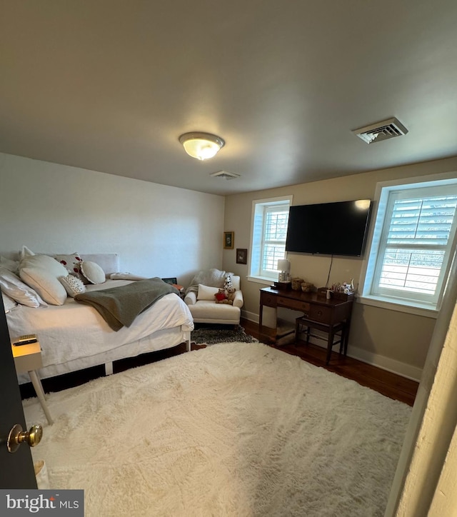 bedroom with wood finished floors, visible vents, and baseboards