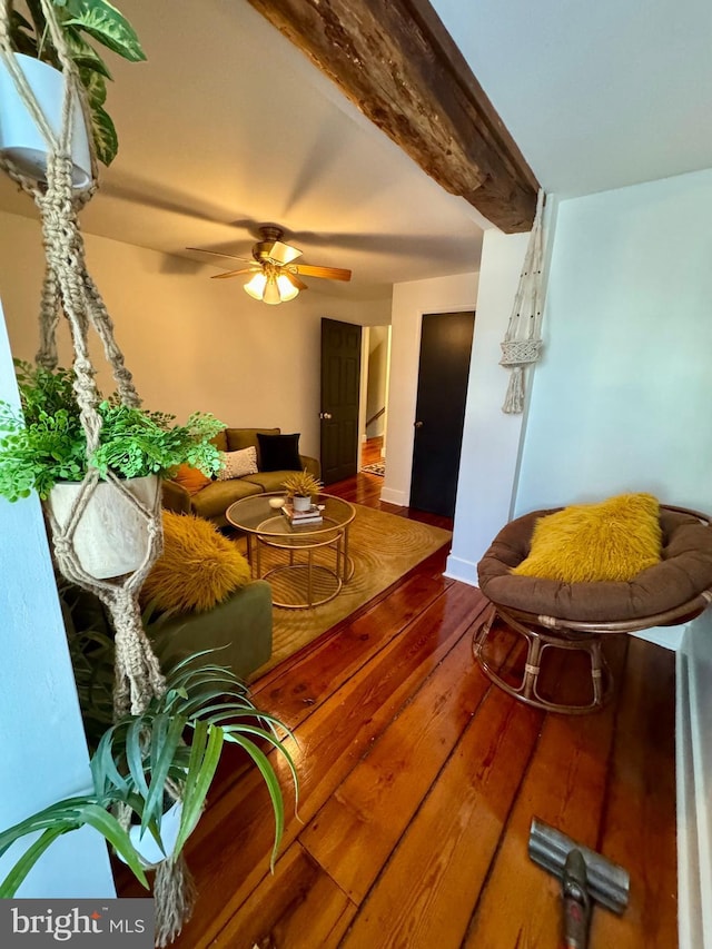 living room with ceiling fan, wood finished floors, beam ceiling, and baseboards