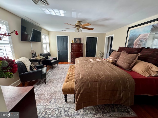 bedroom featuring a ceiling fan, visible vents, and wood finished floors