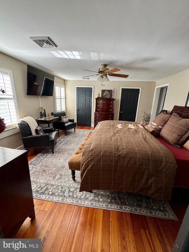 bedroom featuring hardwood / wood-style flooring, ceiling fan, and visible vents