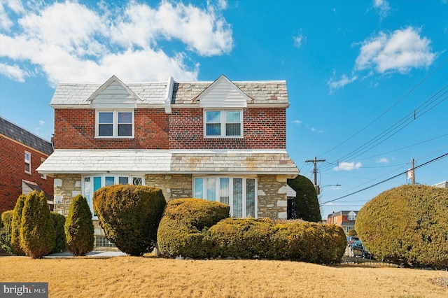 view of front of property featuring stone siding, a high end roof, brick siding, and a front lawn