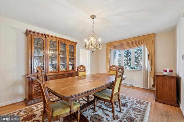 dining area with light wood-style floors, visible vents, a chandelier, and baseboards