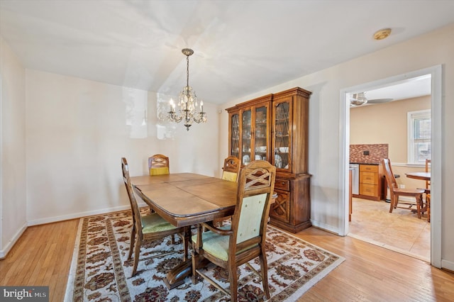 dining area with an inviting chandelier, baseboards, and light wood-type flooring