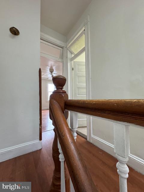 hallway featuring arched walkways, wood finished floors, and baseboards