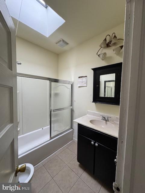 full bathroom featuring a skylight, visible vents, enclosed tub / shower combo, tile patterned floors, and vanity