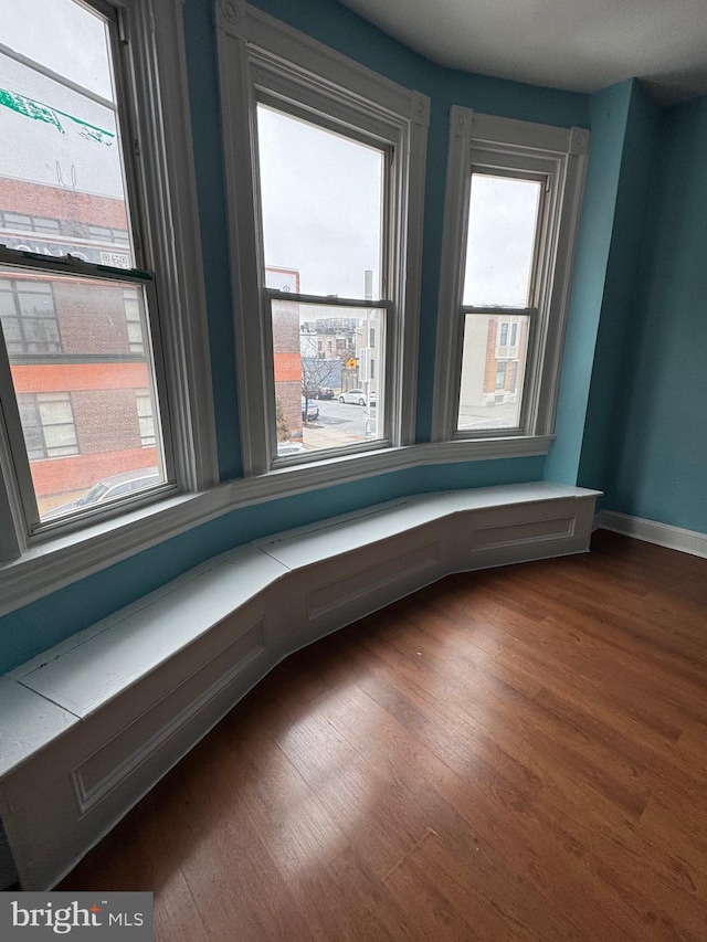 unfurnished room with baseboards and dark wood-style flooring