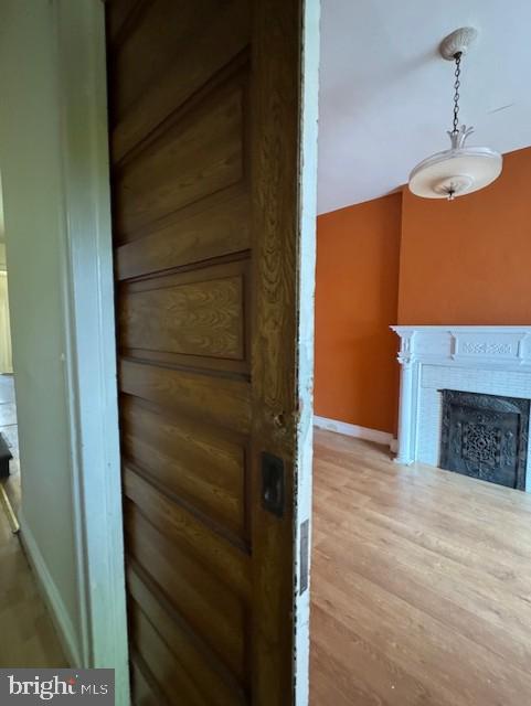 interior details featuring a fireplace, wood finished floors, and baseboards