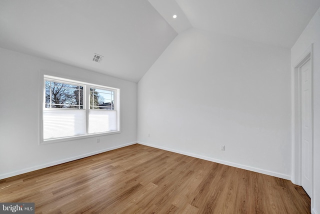 interior space with visible vents, vaulted ceiling, baseboards, and wood finished floors