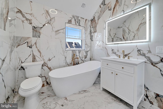 full bath with marble finish floor, a freestanding tub, toilet, and stone wall