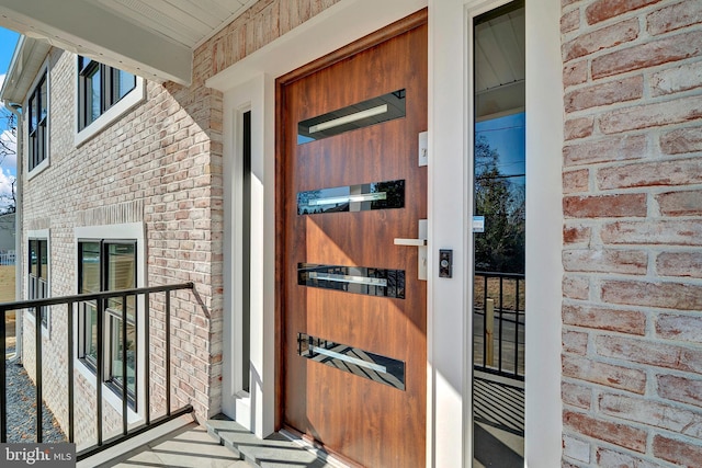 property entrance featuring brick siding and a porch