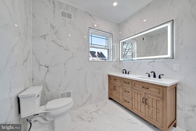 bathroom featuring marble finish floor, visible vents, a sink, and stone wall