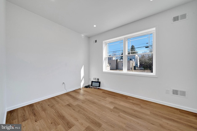 spare room featuring wood finished floors, visible vents, and baseboards