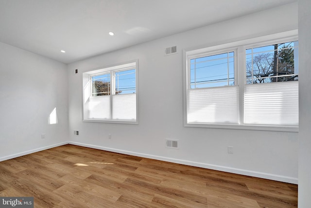 empty room with recessed lighting, visible vents, baseboards, and wood finished floors