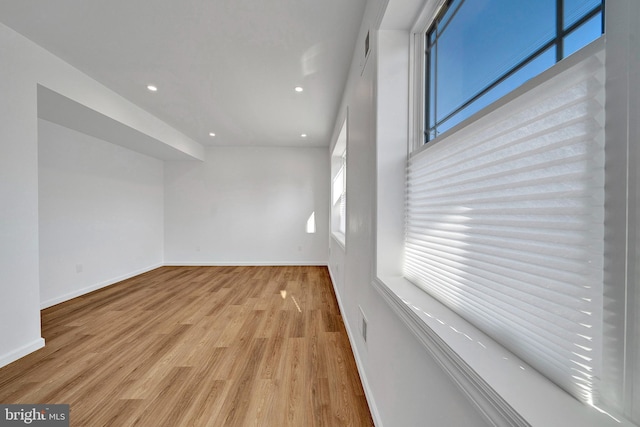 unfurnished room featuring baseboards, wood finished floors, and recessed lighting