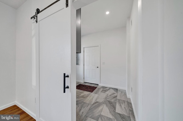 corridor with recessed lighting, baseboards, and a barn door