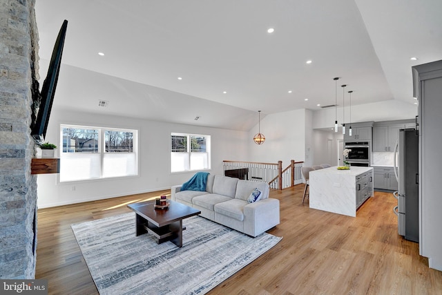 living room featuring lofted ceiling, recessed lighting, visible vents, baseboards, and light wood-type flooring