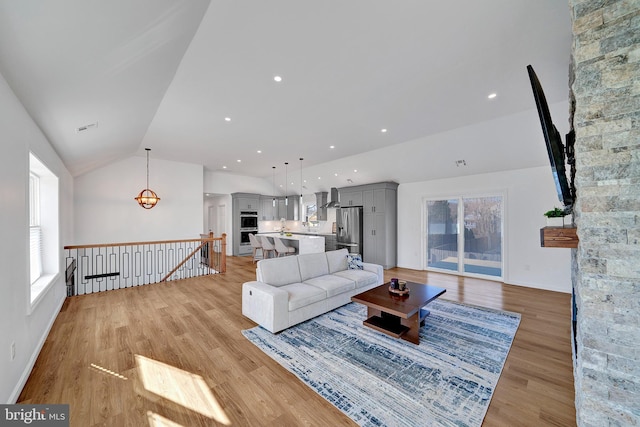 living area with recessed lighting, visible vents, vaulted ceiling, and light wood finished floors