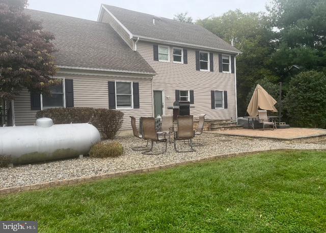 rear view of property featuring a lawn and a patio area