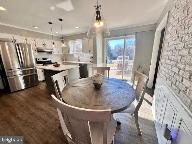 dining room featuring recessed lighting, dark wood-style flooring, crown molding, and brick wall