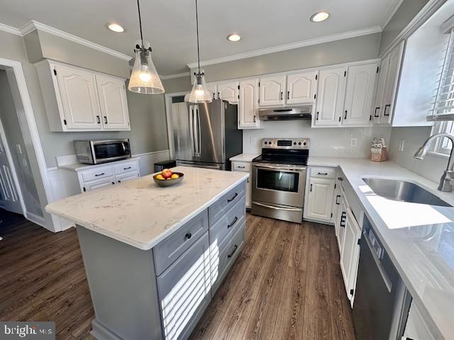 kitchen with white cabinets, appliances with stainless steel finishes, light stone countertops, under cabinet range hood, and a sink