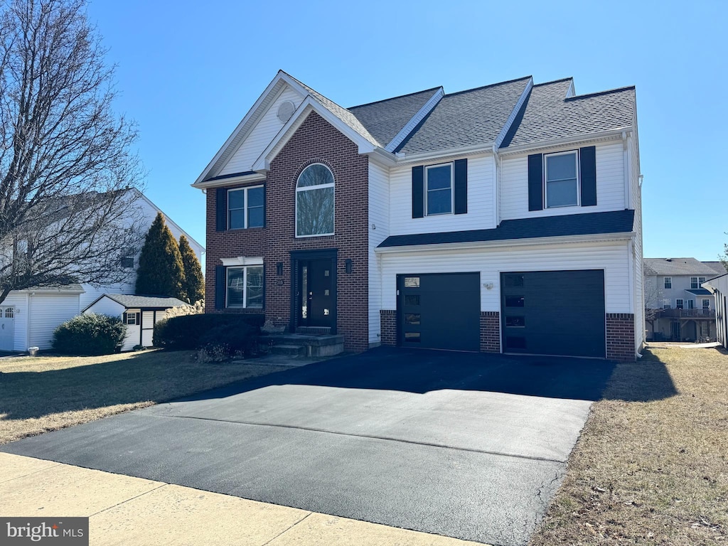 view of front of home featuring aphalt driveway, brick siding, and a garage