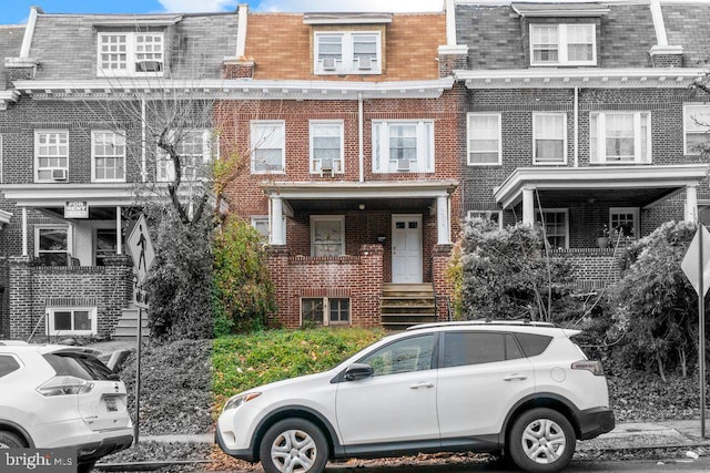 townhome / multi-family property featuring mansard roof and brick siding